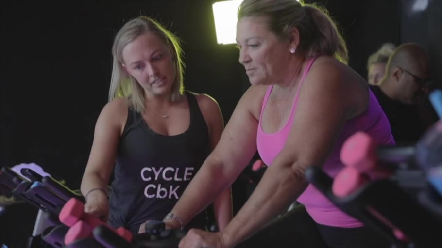 A CbK coach helping a rider with her hand weights